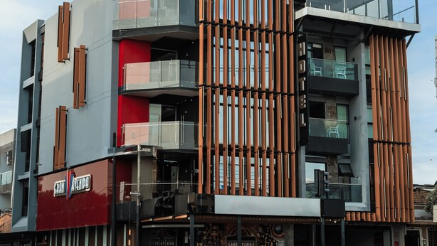 Un edificio moderno de varios pisos con una combinación de balcones y grandes ventanales.