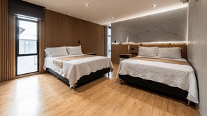 Una habitación de hotel moderna con dos camas, piso de madera y un ventanal grande.