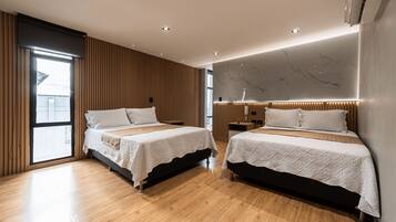 A modern hotel room with two beds, wooden flooring, and a large window.