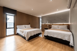 Ein modernes Hotelzimmer mit zwei Betten, Holzboden und einem großen Fenster.