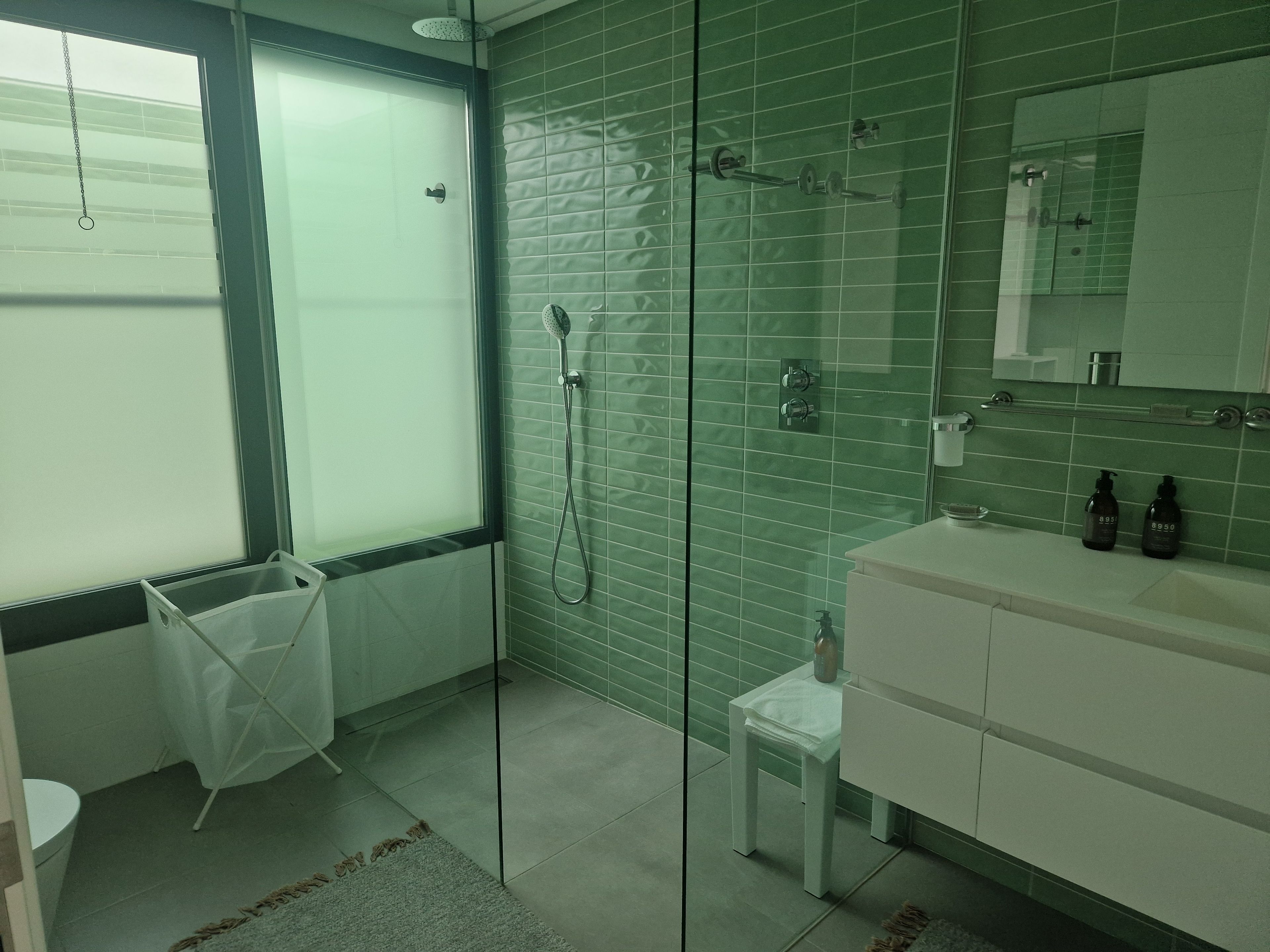 Une salle de bain avec une douche à parois de verre, un lavabo blanc et un miroir au-dessus du lavabo.