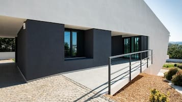 Ein modernes Gebäude mit flachem Dach, großen Fenstern und einem Betonweg, der zu einer Metalltreppe führt.