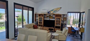 A modern living room with a sofa, chairs, a TV, and a bookshelf. - Heading South Private Oasis (Quarteira)