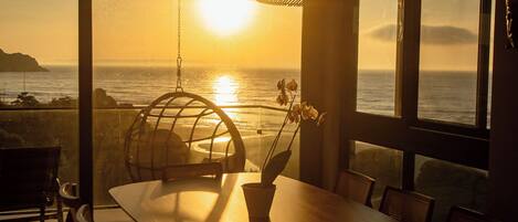 Un comedor con vista al océano al atardecer.