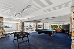 Amplio espacio interior con mesa de billar, mesa de futbolín y zona de bar.