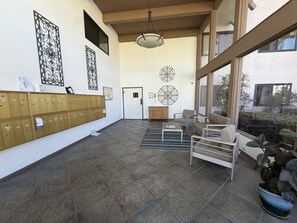 A lobby with a row of lockers, a reception desk, and a seating area with a view of the outdoors. - Cute San Clemente 1BDRM Condo - Minutes To Beach (San Clemente)