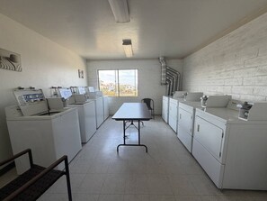 Lavandería con electrodomésticos blancos, una mesa y un ventanal con vistas.