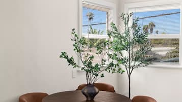 Een eetruimte met een ronde tafel, zes stoelen en een vaas met planten.