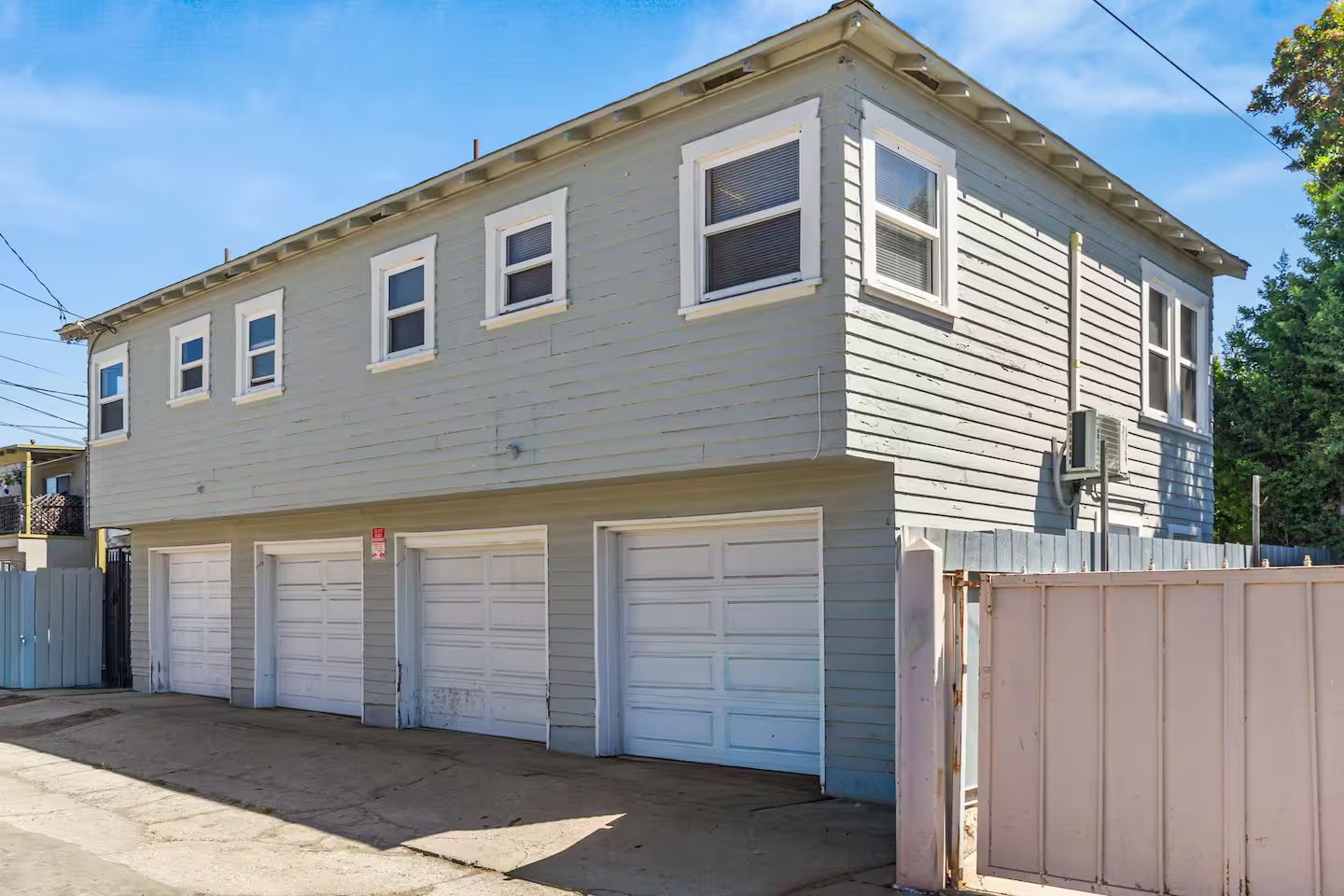 A two-story residential building with a garage and a fenced yard.