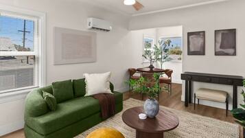 A modern living room with a green sofa, a round coffee table, and a dining area with a table and chairs.