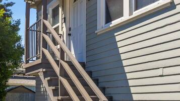 A residential building with a staircase leading to a covered porch area.