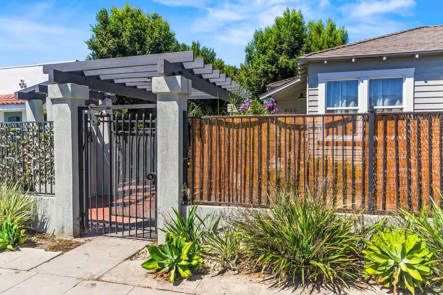 A residential property with a gated entrance, a pergola, and a wooden fence.