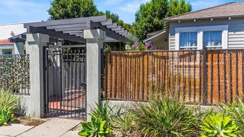 A residential property with a gated entrance, a pergola, and a wooden fence.
