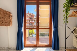 Ein Zimmer mit einer Schiebetür zum Balkon, einem Heizkörper und einer Pflanze.