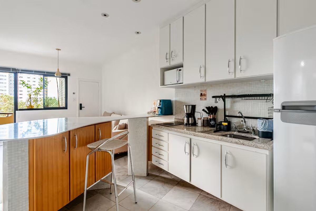 A modern kitchen with white cabinets, a granite countertop, a built-in oven, and a large window providing natural light.