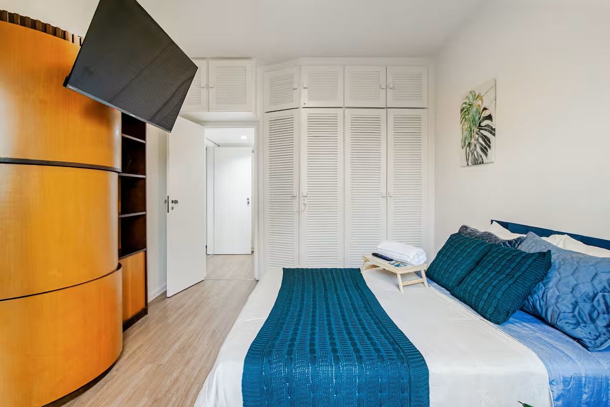 A bedroom with a bed, a wardrobe, and a television.