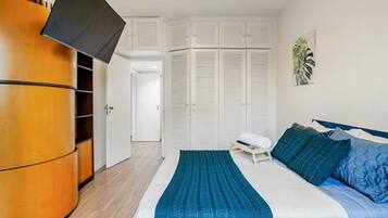 A bedroom with a bed, a wardrobe, and a television.
