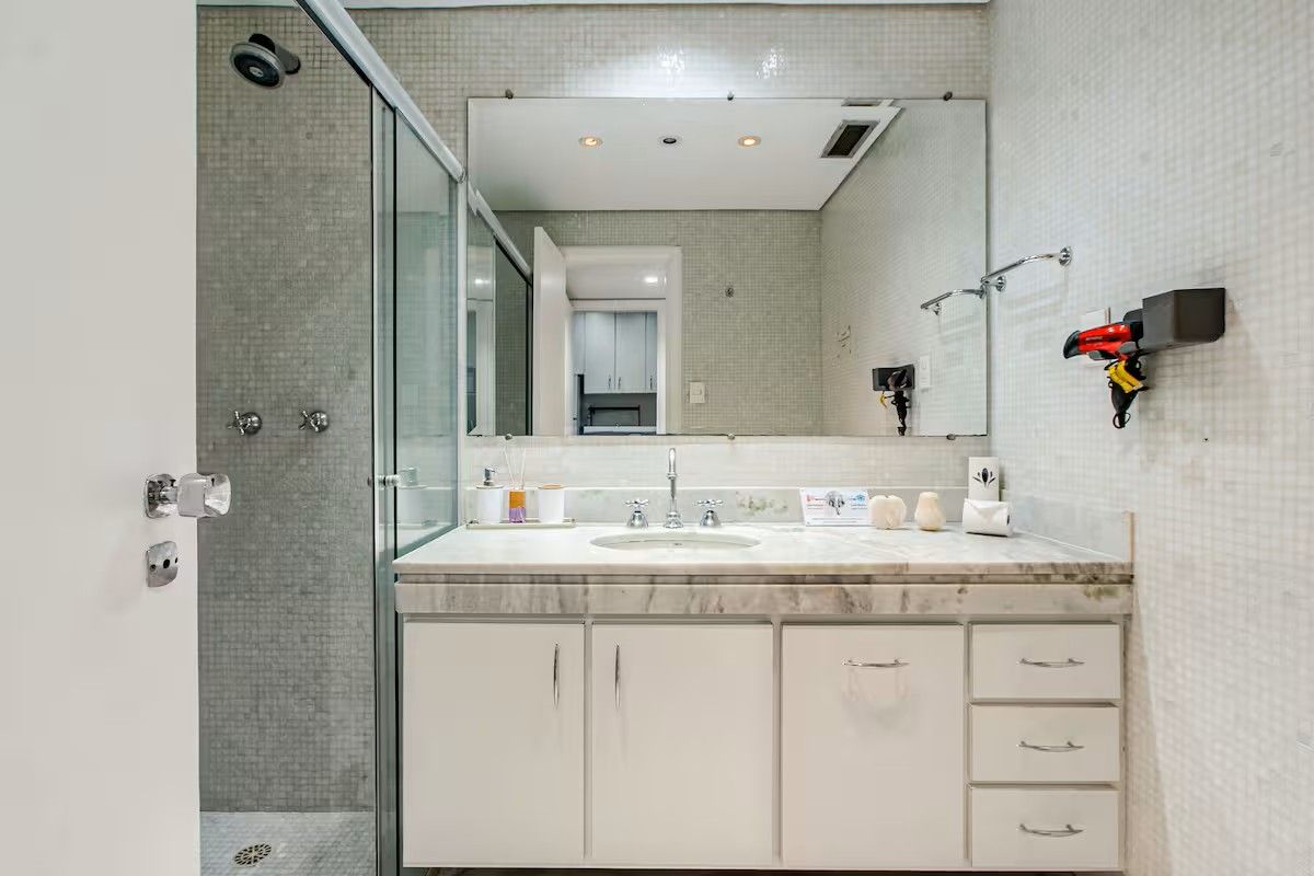 Un baño moderno con cabina de ducha de vidrio, lavamanos de mármol y un espejo grande.