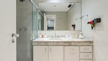 Un baño moderno con cabina de ducha de vidrio, lavamanos de mármol y un espejo grande.