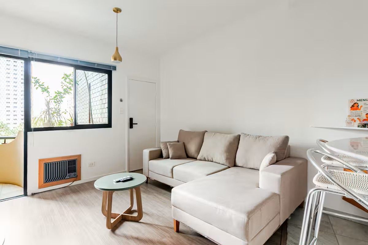 Una sala de estar moderna con un sofá modular, una mesa de centro redonda y una zona de comedor con una silla de metal.