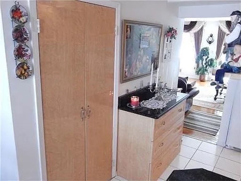 Quarto com armário de madeira, pia com um prato decorativo e espelho acima.