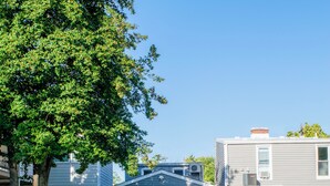 Een achtertuin met gazon, terras en tuinmeubilair, en een witte schutting.