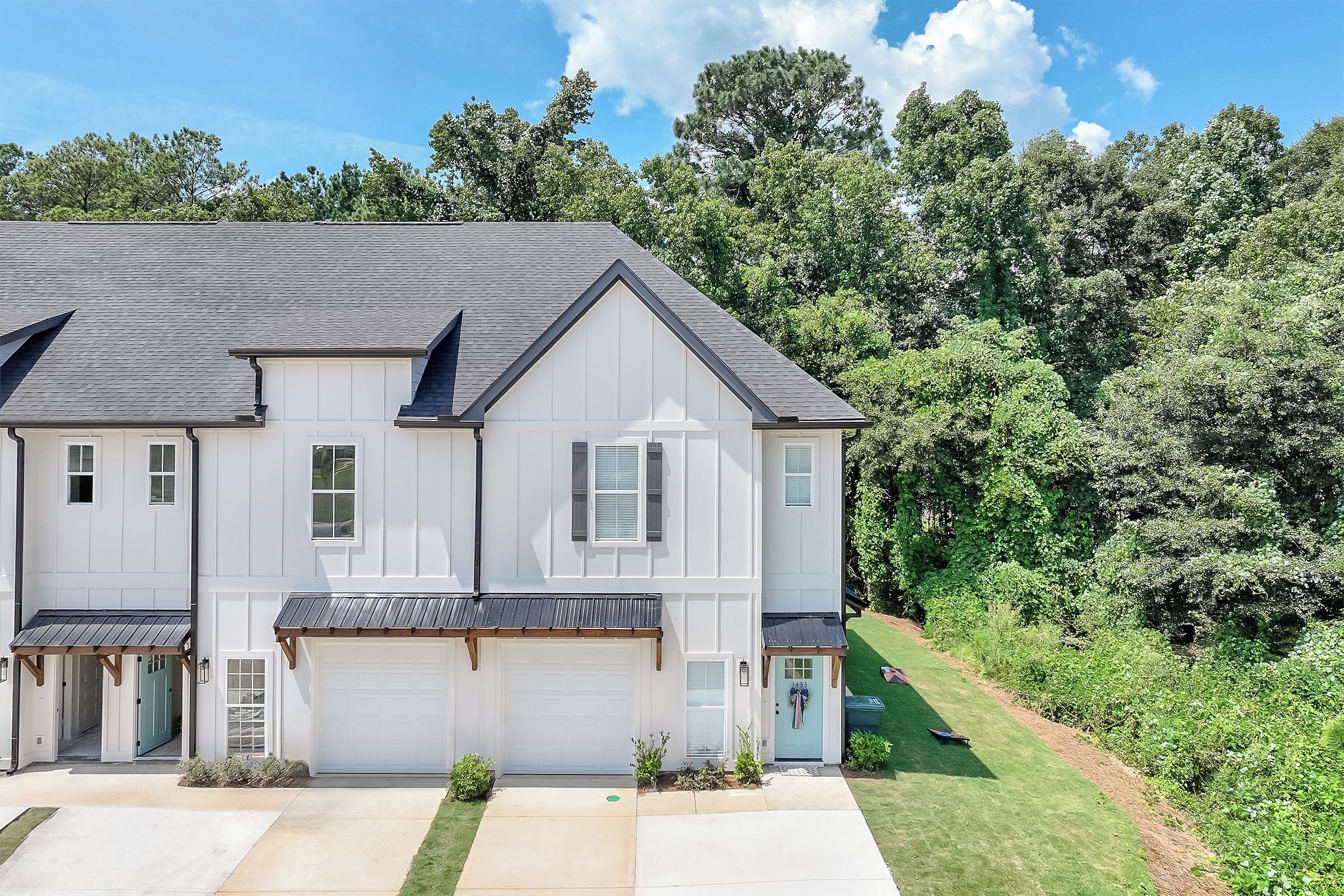 A two-story residential building with a garage, a covered porch, and a well-maintained lawn.