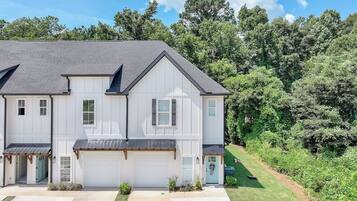 A two-story residential building with a garage, a covered porch, and a well-maintained lawn.