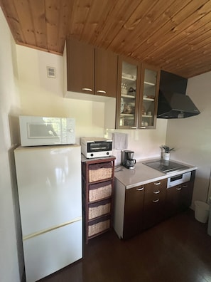 A compact kitchen with a microwave, toaster, coffee maker, and wooden cabinets.