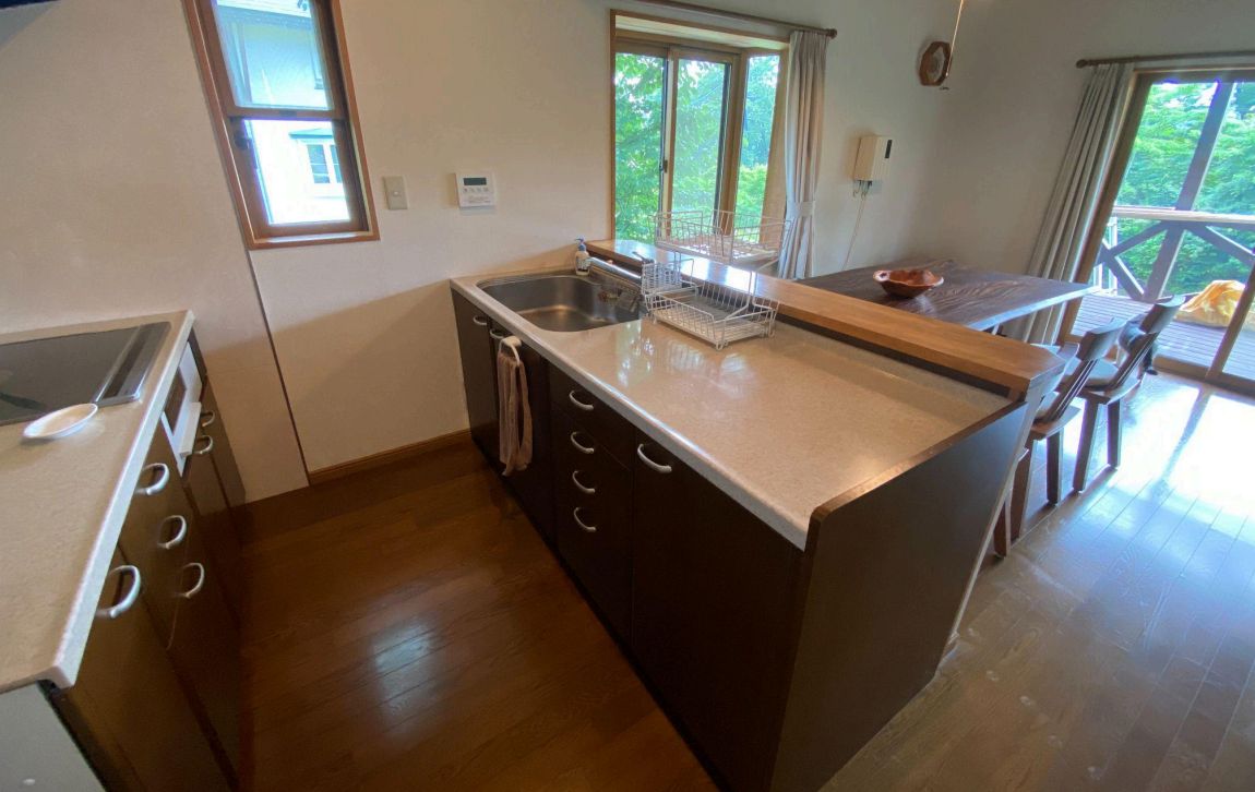 A kitchen with a wooden countertop, a sink, and a window overlooking greenery.