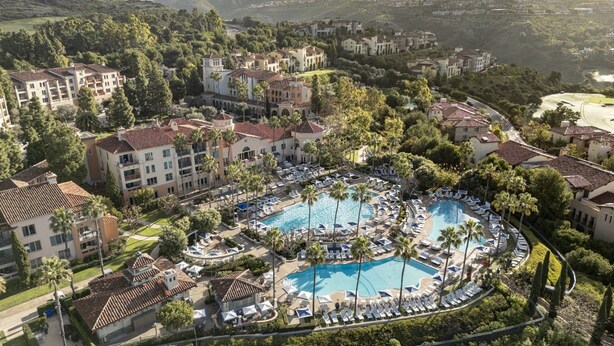 An aerial view of a resort with multiple buildings, a central pool area with sun loungers, and surrounding greenery. - Resort with 2 bedrooms and AC in perfect Newport Coast (newport Coast)