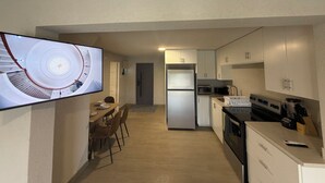 A modern kitchen with a built-in oven, microwave, and refrigerator. There is a dining area with a table and chairs. - 2 bed 1 bath apartment w/ AC, WIFI, kitchen & 5 min walk to west coast beaches (Appleby)