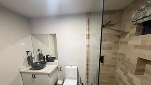 A bathroom with a glass-enclosed shower, a white toilet, and a large bowl sink. - 2 bed 1 bath apartment w/ AC, WIFI, kitchen & 5 min walk to west coast beaches (Appleby)