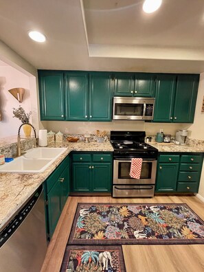A kitchen with green cabinets, stainless steel appliances, and a granite countertop. - Artsy Townhome / Pool & Spa / Attached Garage / North Hollywood (Los Angeles)