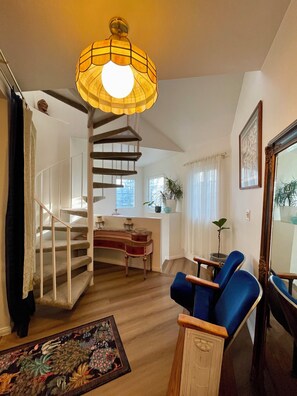 A staircase leading to a landing with a dining area, a blue armchair, and a large mirror. - Artsy Townhome / Pool & Spa / Attached Garage / North Hollywood (Los Angeles)