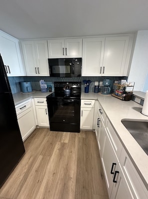 A modern kitchen with white cabinets, a black oven, and a microwave. - Family-Friendly 3BR | Indoor Pools & Arcade (Myrtle Beach)