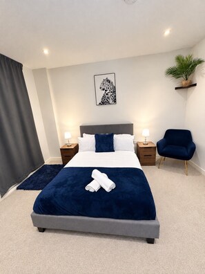 A neatly arranged bedroom with a bed, bedside tables, a chair, a wall-mounted plant, and a ceiling light. - Manchester City Centre, Spacious, Luxury, Apartment (Manchester)