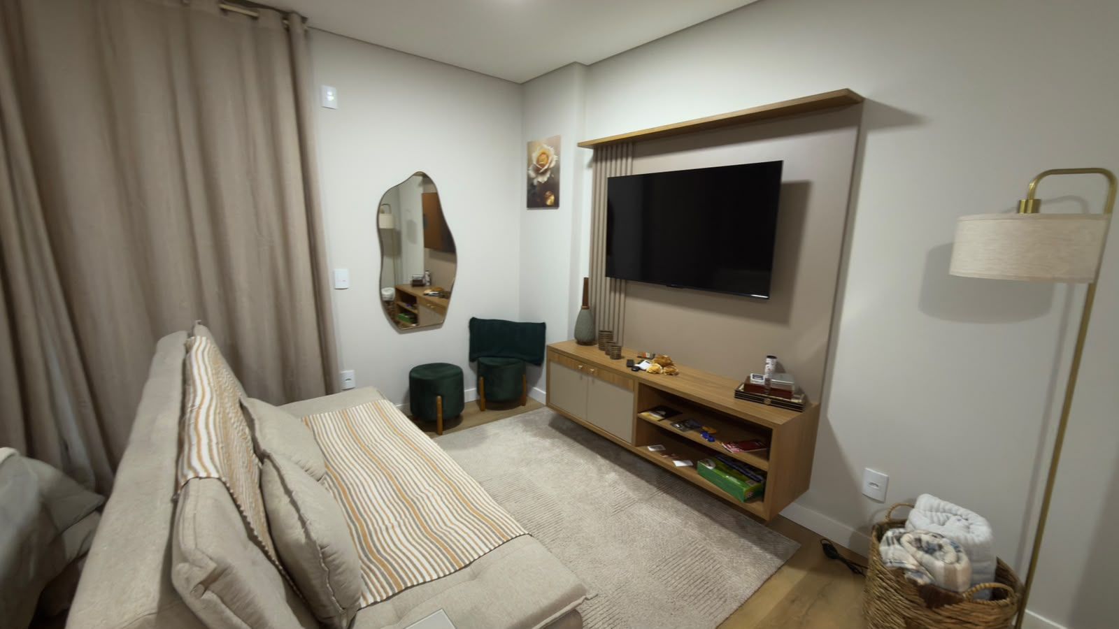 A modern living room with a sofa, a TV mounted on the wall, a wooden console table, and a floor lamp.