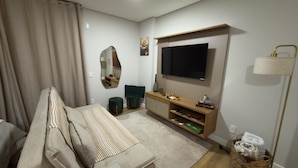A modern living room with a sofa, a TV mounted on the wall, a wooden console table, and a floor lamp. - 303 Avenida Principal Urubici (Urubici)