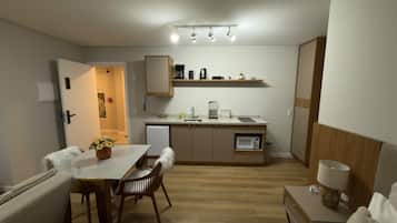 A compact kitchen with a dining area, a microwave, a coffee maker, and a small refrigerator.