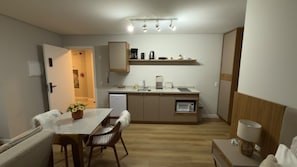 Ett kompakt kök med en matplats, en mikrovågsugn, en kaffebryggare och ett litet kylskåp.