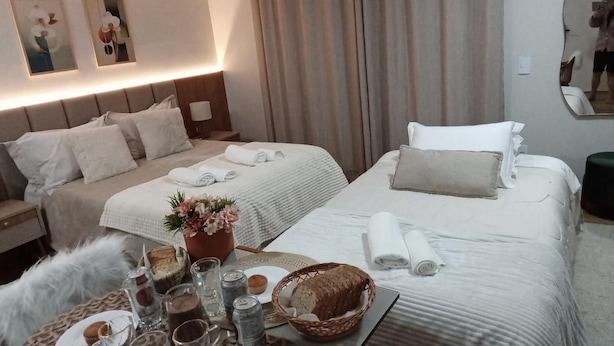 A hotel room with two beds, a bedside table with a lamp, a mirror, and a wall-mounted air conditioner. - 303 Avenida Principal Urubici (Urubici)