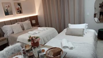 A hotel room with two beds, a bedside table with a lamp, a mirror, and a wall-mounted air conditioner.