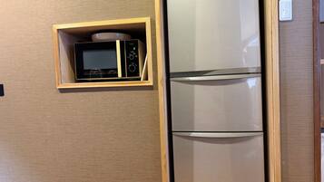 A kitchen with a microwave and a stainless steel refrigerator.