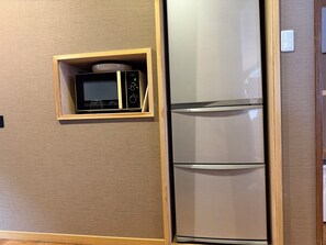 A kitchen with a microwave and a stainless steel refrigerator.