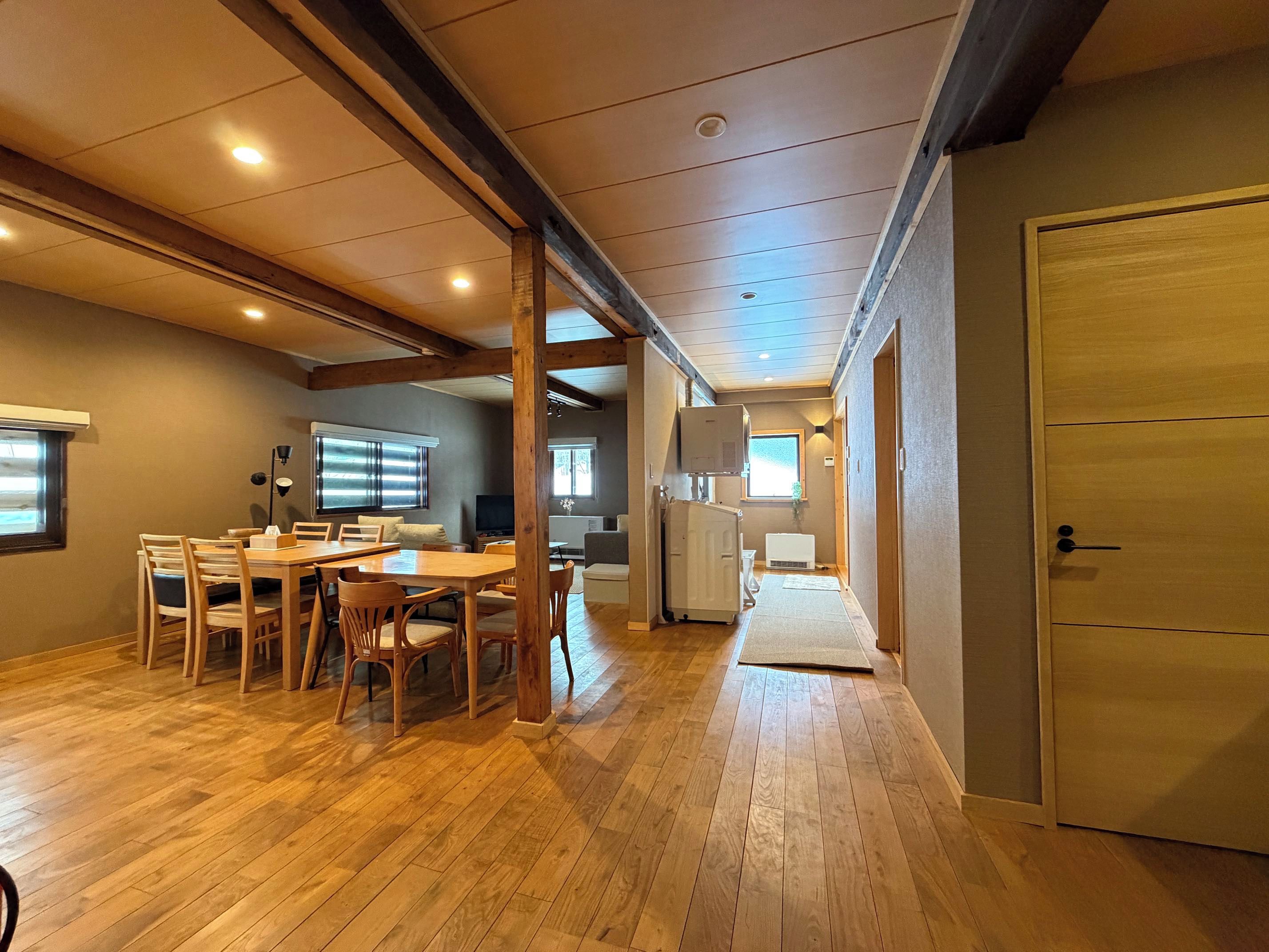 A spacious room with a wooden dining table and chairs, a television, and a radiator.