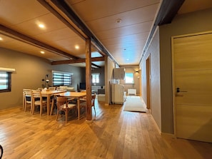 Ein geräumiges Zimmer mit einem Holzespeisetisch und Stühlen, einem Fernseher und einer Heizung.
