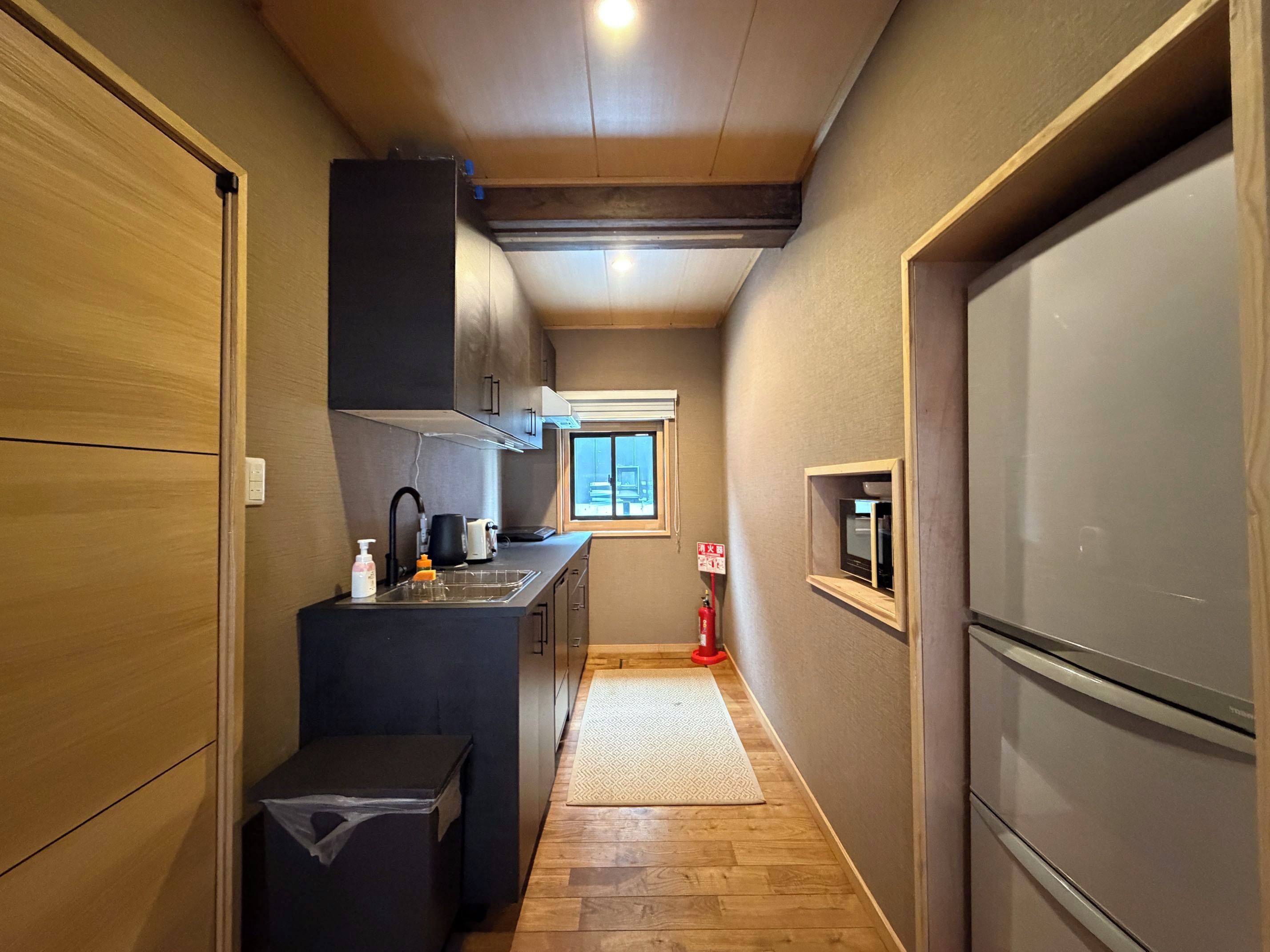 A narrow kitchen with a built-in refrigerator, a sink, and a window providing natural light.