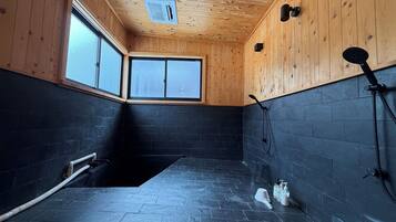 Une salle de bain avec des murs en bois, un sol carrelé de noir et une fenêtre.