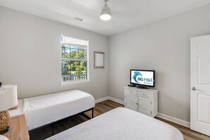 A bedroom with two single beds, a television on a cabinet, and a window with a view of greenery. - Large 2BR Unit with Pool Access, River Oaks Golf (Myrtle Beach)